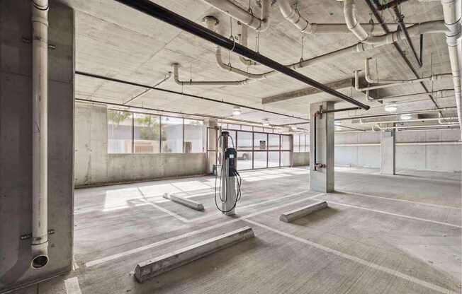 A parking garage with a concrete floor and walls, and a concrete pillar on the left.