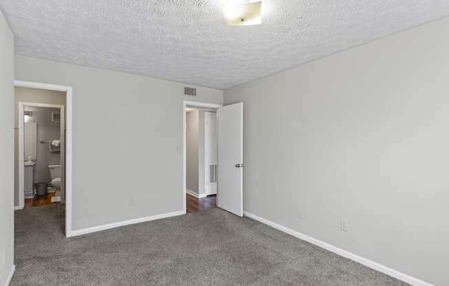 A room with a carpeted floor and a doorway leading to another room.