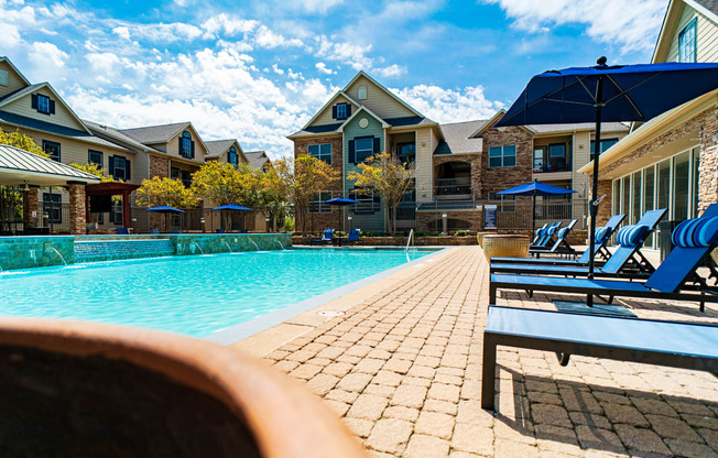 a swimming pool with blue chairs and buildings in the background