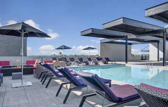 a pool with lounge chairs and umbrellas on top of a building