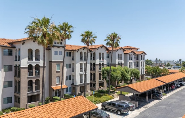 A row of apartment buildings with a parking lot in front.