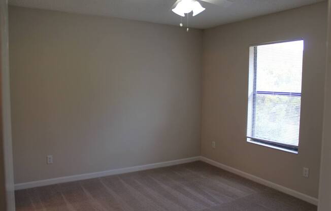 A room with a window and a ceiling fan.