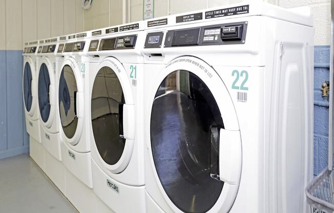 A row of white front load washing machines with the number 22 on the front.