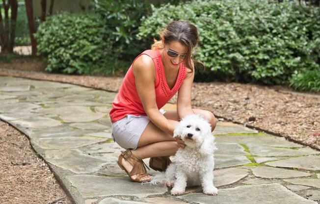 a woman is petting a white dog on the ground