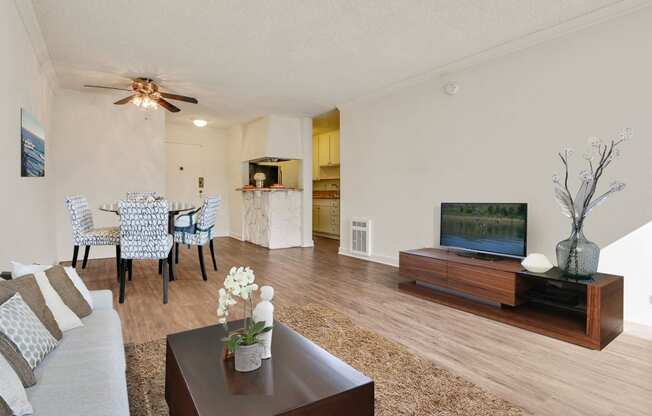 Living room with wood inspired flooring, dining area with ceiling Fan, kitchen with breakfast bar