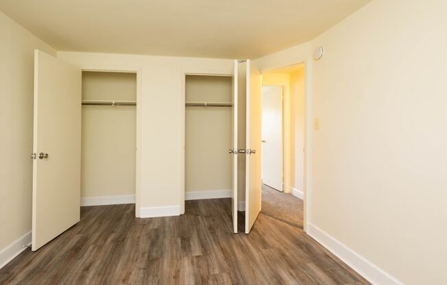 a bedroom with two closets and hardwood floors