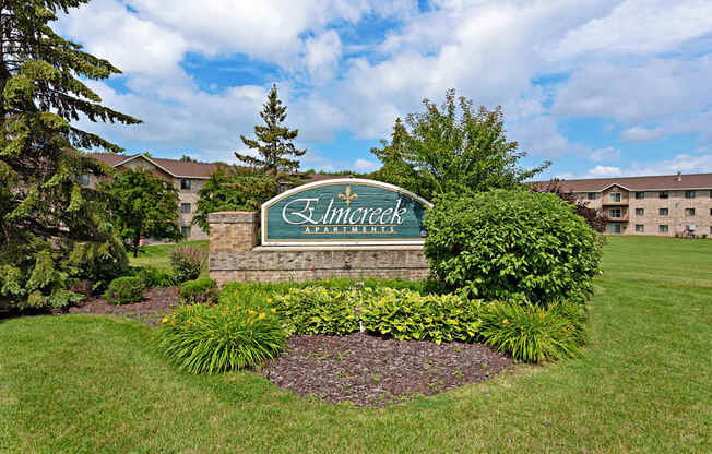 A sign that says "Elmcroft Apartments" in front of a building.