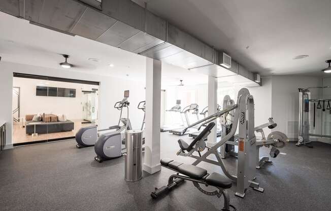 a gym with cardio equipment and a living room with a couch