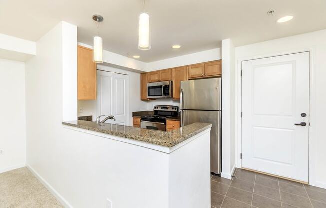 a kitchen with a granite counter top and a stainless steel refrigerator  at Delano, Redmond, 98052