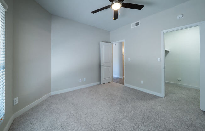 a bedroom with gray walls and a ceiling fan
