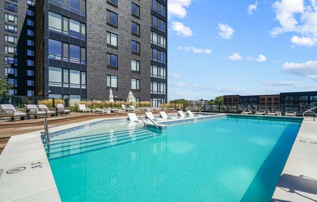 a swimming pool with chaise lounge chairs and a building in the background