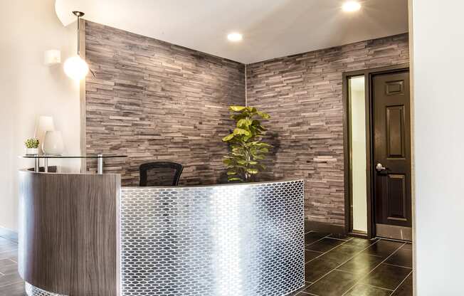 a curved reception desk in a hotel lobby with a brick wall