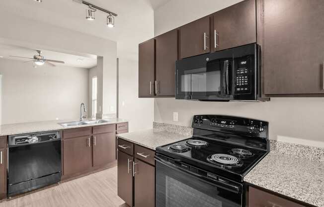 an empty kitchen with black appliances and granite counter tops