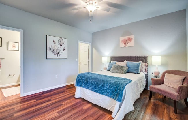 a bedroom with a bed and a chair and a ceiling fan