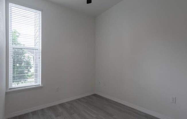 A room with a window and wooden flooring.