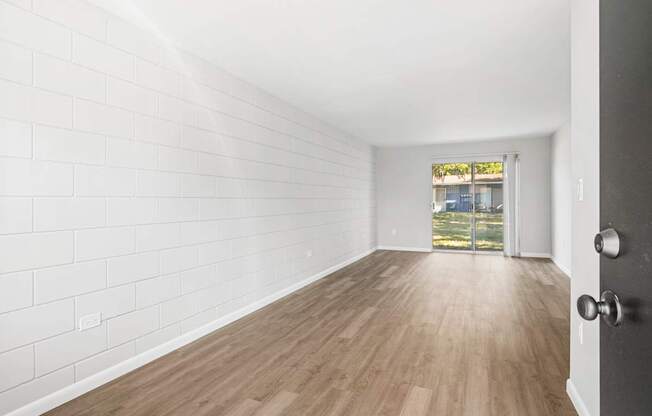 A room with white walls and wooden flooring with a door on the right.