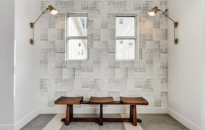 Seating Area with Wooden Bench, Windows, and Wall Mounted Lamps at Morgan Ranch Apartments, California
