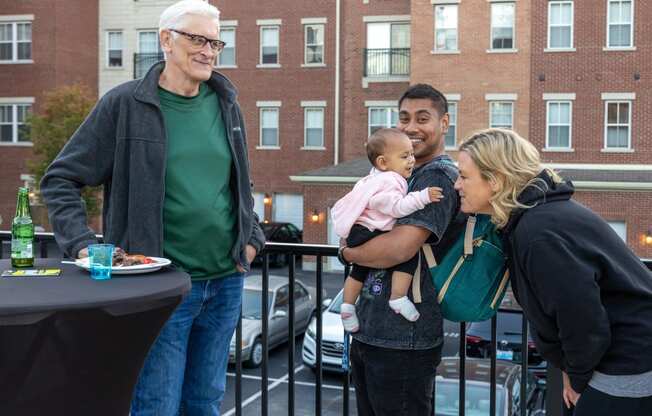 people standing on a balcony holding a baby and a woman holding a child