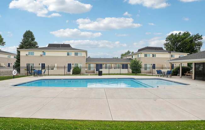 A swimming pool in front of a building with a fence around it.