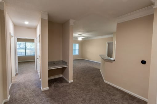 an empty living room and hallway with a tv and a window