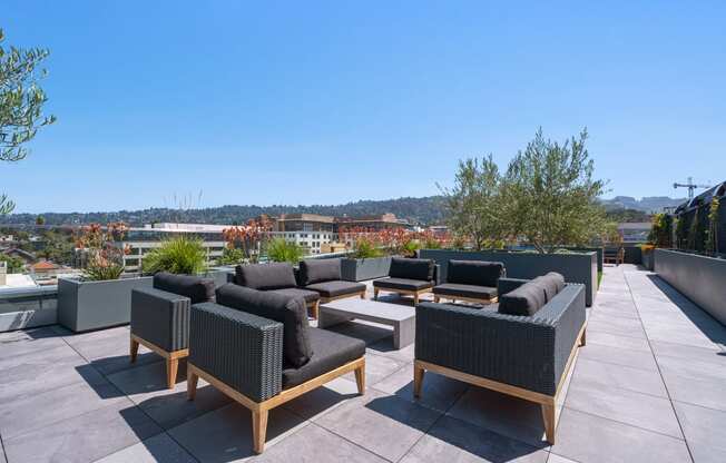 a roof top patio with furniture and a city in the background