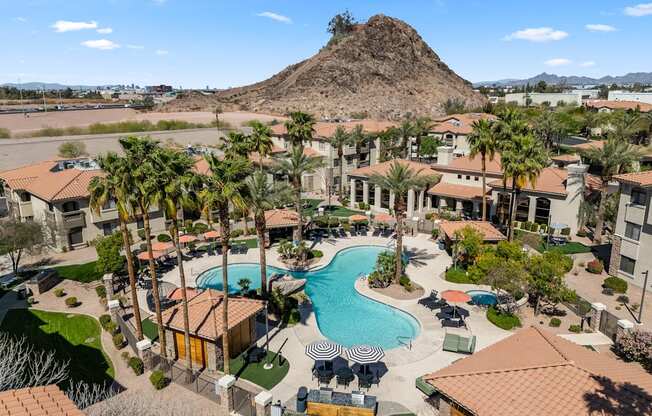 A large swimming pool surrounded by palm trees and buildings.