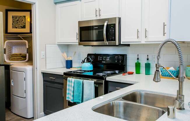 A kitchen with a stove, sink, and refrigerator.