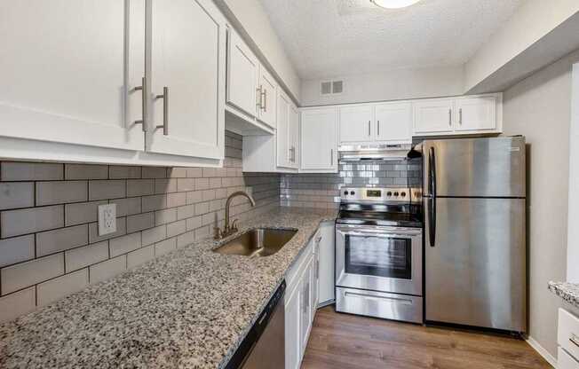 A kitchen with a stainless steel refrigerator, oven, and sink.