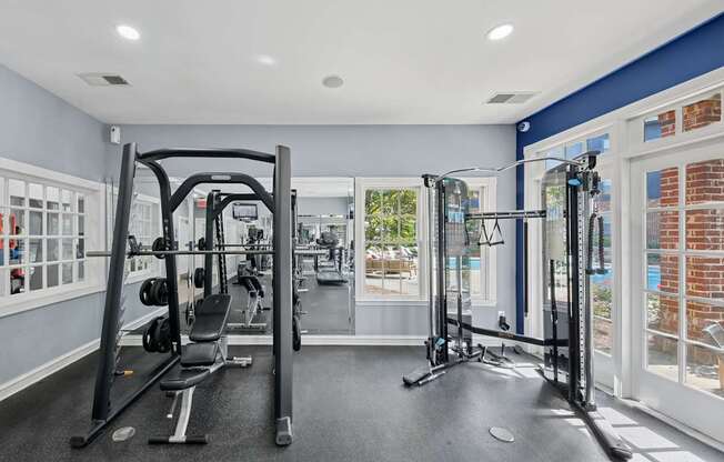 A gym with a variety of equipment including a squat rack, a leg press machine, and a bench press.