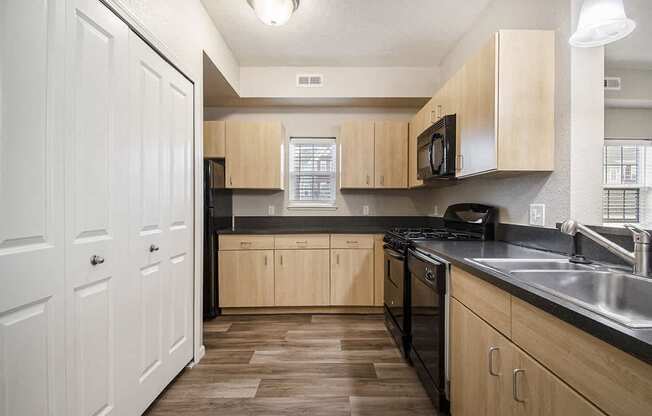 A kitchen with a window, wooden cabinets and black appliances at Lynbrook Apartments and Townhomes, Elkhorn, NE, 68022