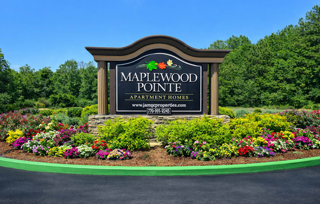 A sign for Maplewood Pointe Apartment Homes is surrounded by flowers.