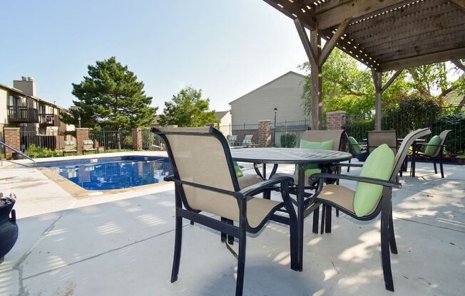 a patio with a table and chairs next to a pool