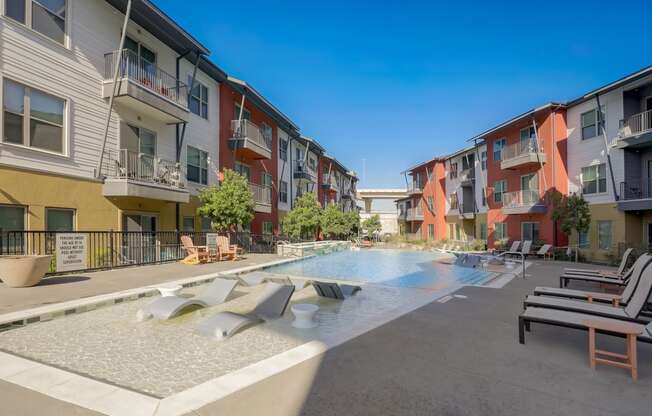 an apartment building with a pool and chairs in front of it