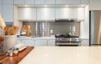 a large white kitchen with stainless steel appliances and white counter tops