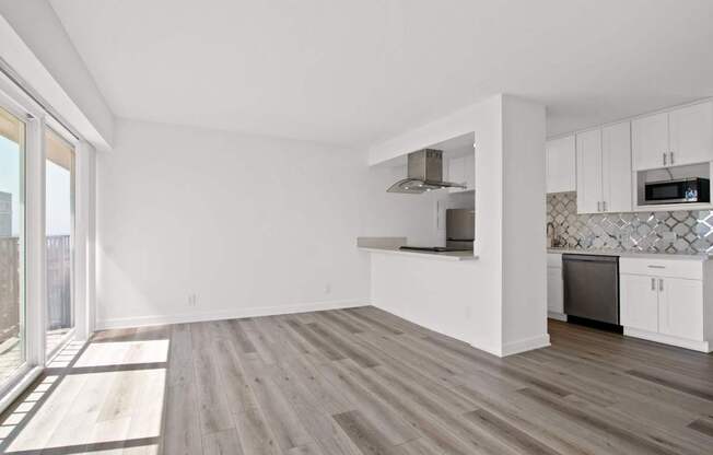 A kitchen with white cabinets and a wooden floor.