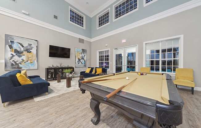 Community Clubhouse with Lounge Furniture and Pool Table Area at Vinings at Hunter's Green Apartments in Tampa, FL.