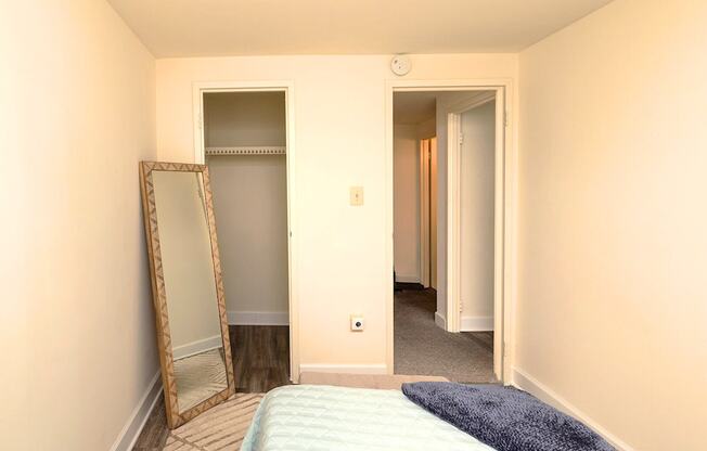 A bedroom with a bed, mirror and wardrobe.
