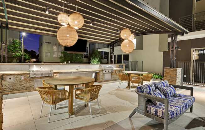 a patio with tables and chairs and an outdoor kitchen