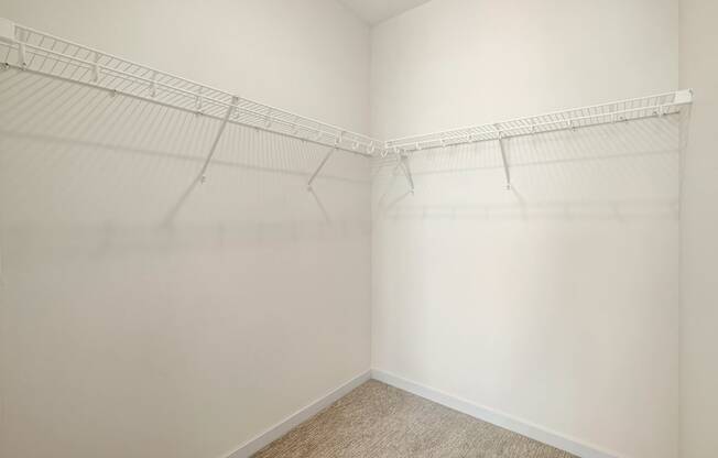 a spacious closet with white walls and shelves and a carpeted floor at The Standard on 32nd, West Fargo, North Dakota