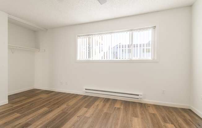 a bedroom with hardwood floors and a large window