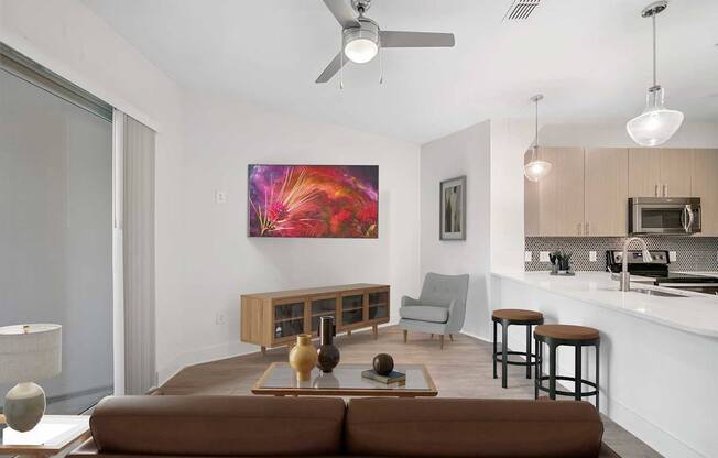 A modern living room with a brown sofa and a painting on the wall.