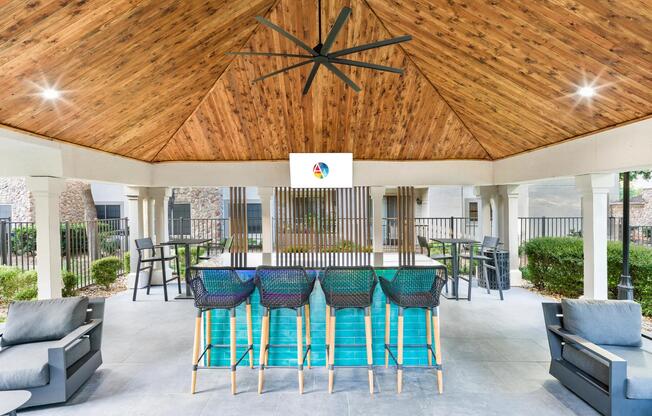 Covered poolside bar with TV, ceiling fan, and plenty of seating—perfect for unwinding or catching the game.