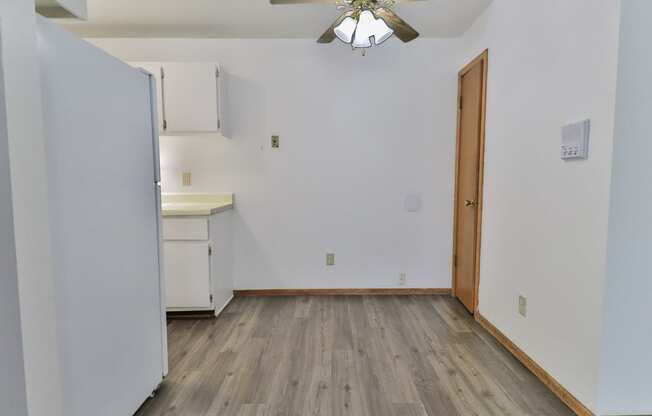 an empty room with white walls and wood flooring and a ceiling fan