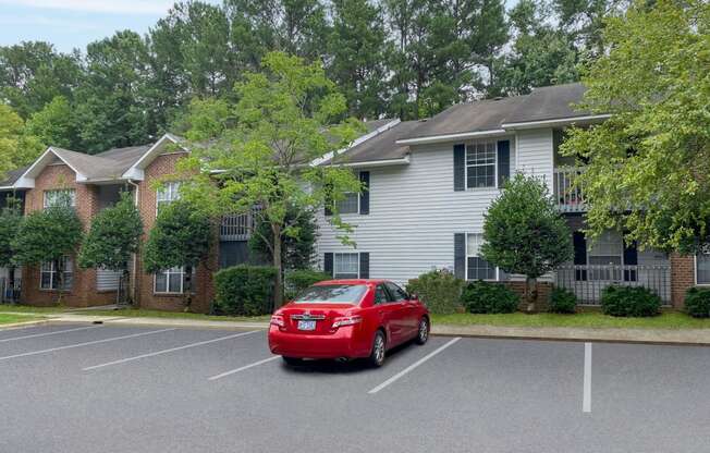 a red car parked in a parking lot in front of a house