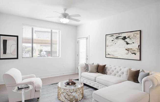 A living room with a white sofa, a white chair, and a coffee table with a decorative design.