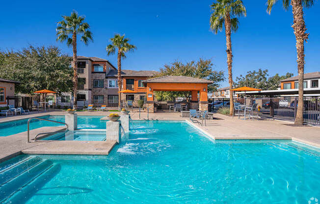 A swimming pool surrounded by palm trees and a building in the background.