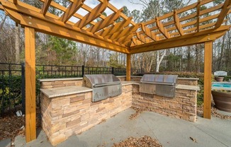 a covered patio with two bbq pits under a wooden roof