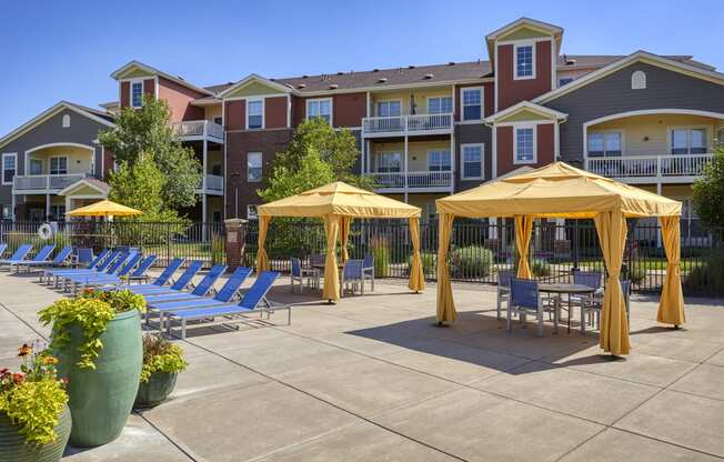 an outdoor patio with yellow umbrellas and chairs at an apartment complex