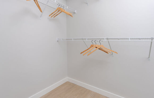 Three wooden hangers are hanging on a white wall.