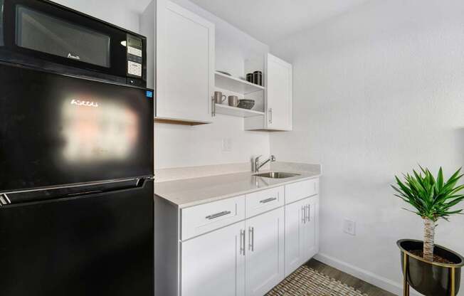 A black microwave oven is on the counter in a white kitchen.